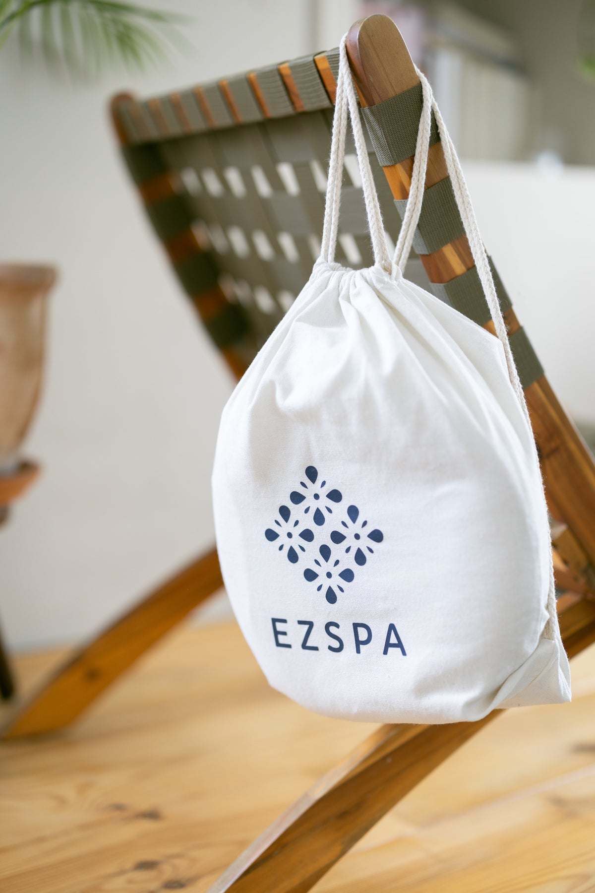 O saco de transporte de algodão da Ezspa com o logotipo, pendurado numa cadeira