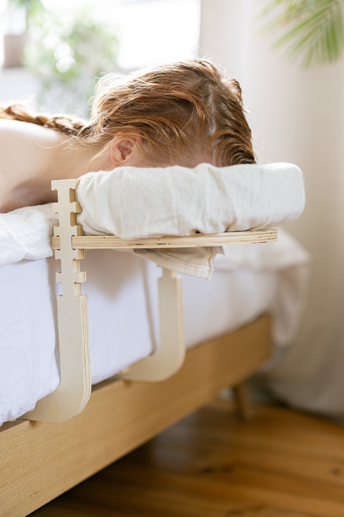 Mulher com trança deitada com a cabeça no apoio de cabeça na borda da cama