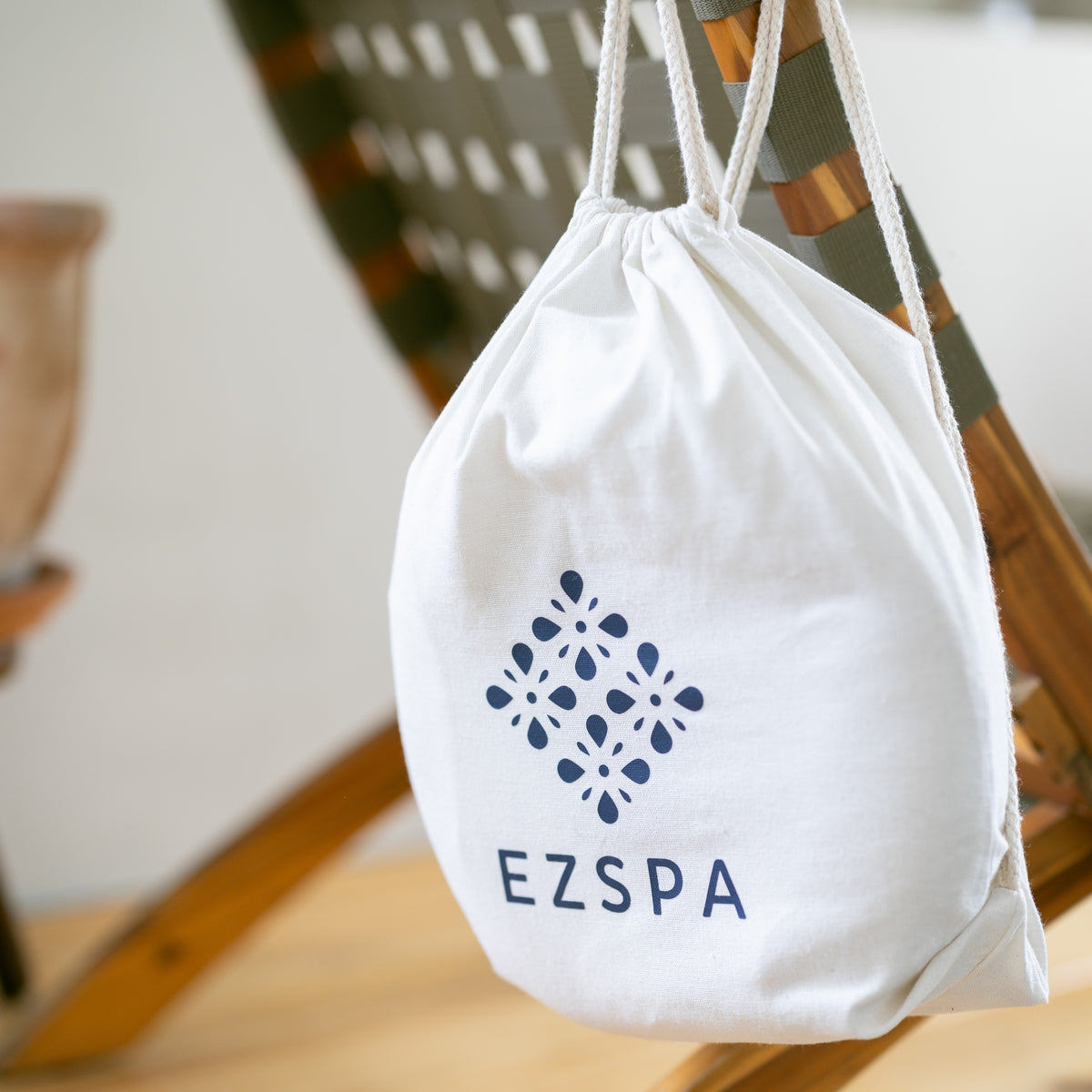 O saco de transporte de algodão da Ezspa com o logotipo, pendurado numa cadeira