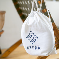 O saco de transporte de algodão da Ezspa com o logotipo, pendurado numa cadeira